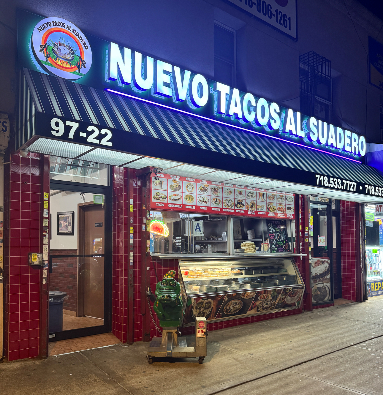 Nuevo Tacos Al Suadero's neon storefront at 97-22 Roosevelt Ave